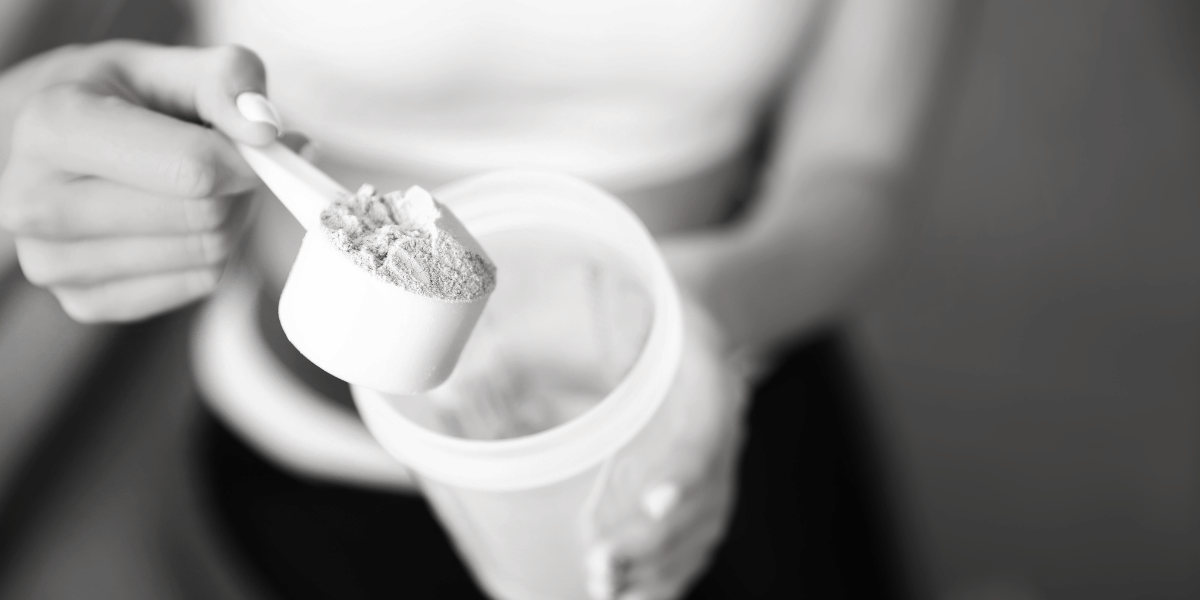 Protein powder being scooped into a shaker bottle