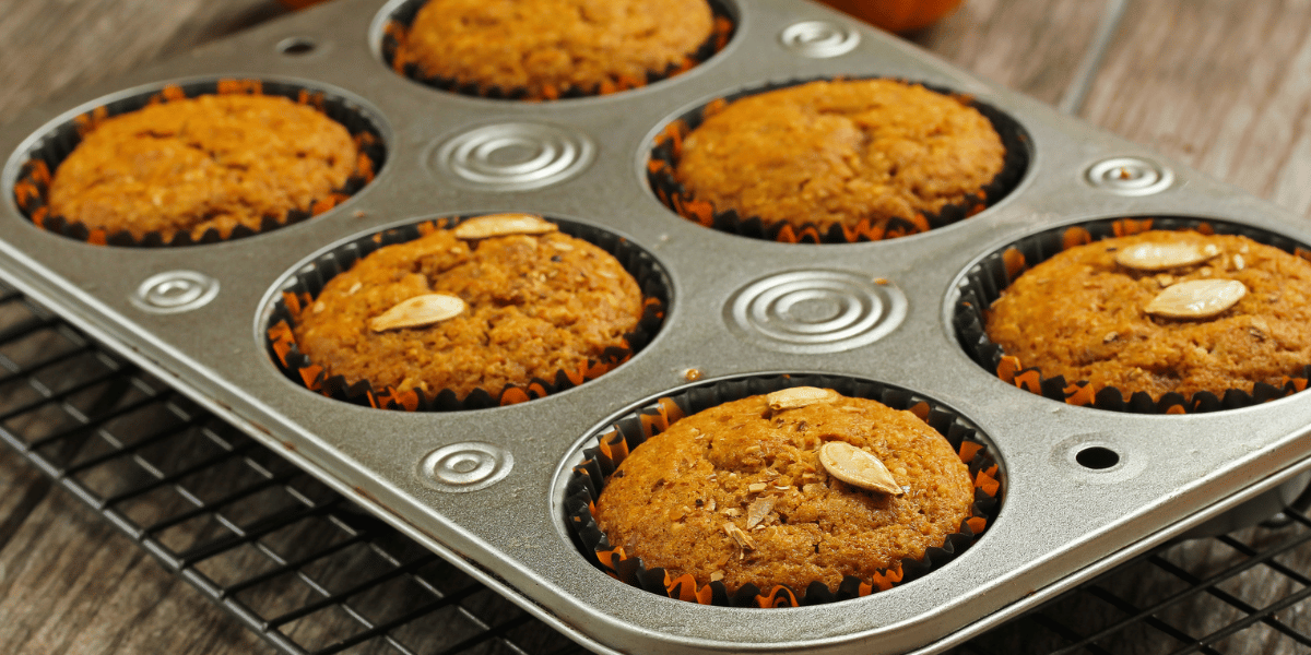 Orange Pumpkin Protein Muffins sitting in a muffin tin