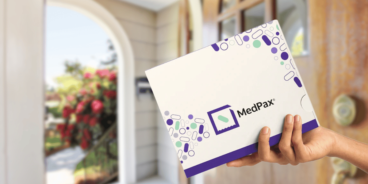 A person holds up a MedPax box that has been delivered to their home
