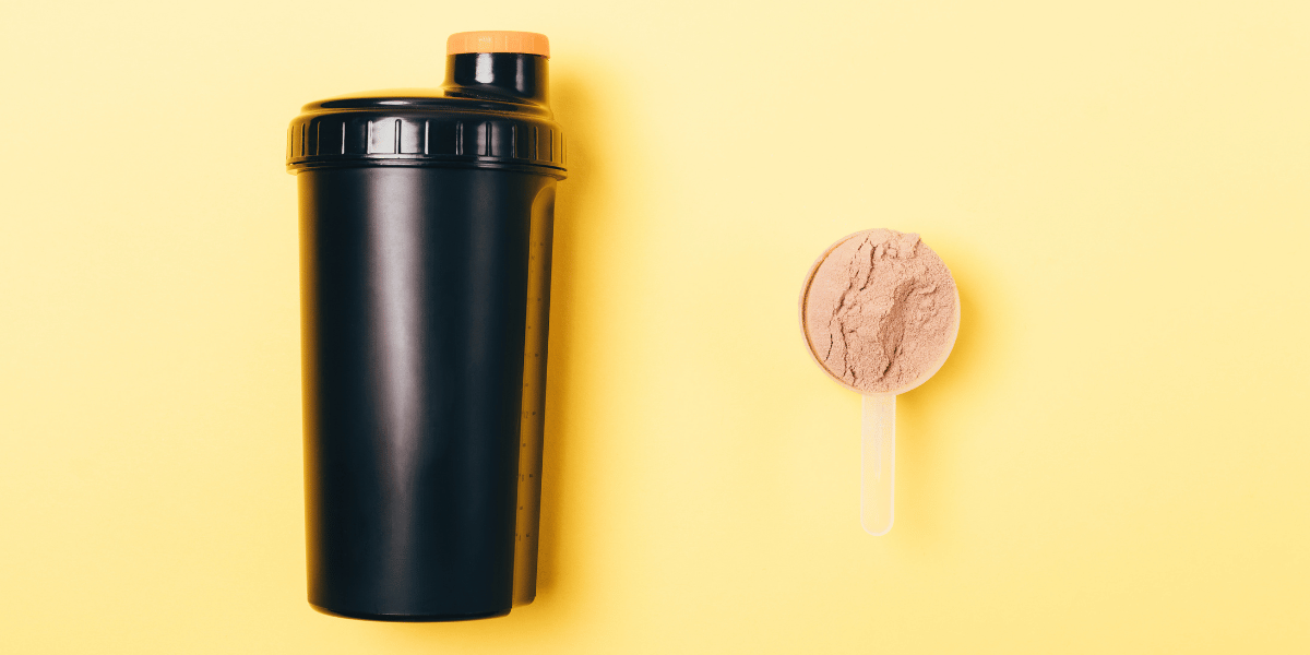 protein powder in scooper next to shaker bottle